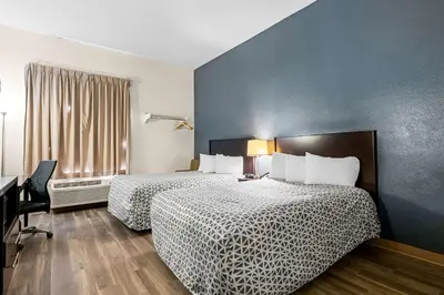 a hotel room with two beds and a desk and a window at Suburban Studios Orlando - Ocoee-Winter Garden in Orlando