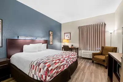 a hotel room with a bed and a chair at Suburban Studios Orlando - Ocoee-Winter Garden in Orlando