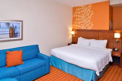 a hotel room with a bed and a blue couch at Fairfield Inn & Suites Orlando Ocoee in Orlando