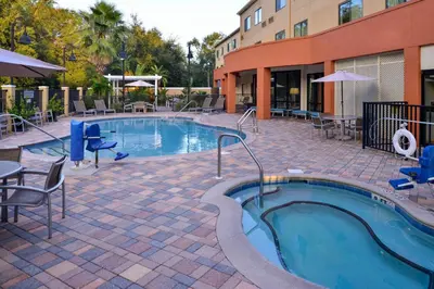 a swimming pool with tables and chairs next to a building at Fairfield Inn & Suites Orlando Ocoee in Orlando