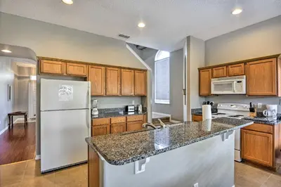 a kitchen with a white refrigerator and wooden cabinets at 10 Mi to Disney Resort Home with Pool and Spa in Orlando