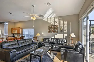 a living room with leather furniture and a ceiling fan at 10 Mi to Disney Resort Home with Pool and Spa in Orlando