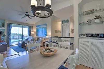 a kitchen and living room with a table and chairs at Lovely Resort Condo Near Disney, Golf and Dining! in Kissimmee