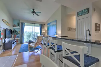 a kitchen and living room with a counter and chairs at Lovely Resort Condo Near Disney, Golf and Dining! in Kissimmee