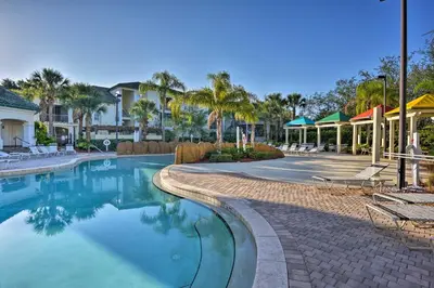 a swimming pool at a resort with chairs and palm trees at Lovely Resort Condo Near Disney, Golf and Dining! in Kissimmee