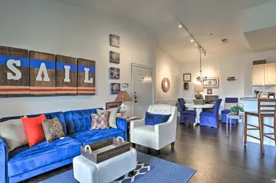 a living room with a blue couch and a kitchen at Resort-Style Condo with Pool 6 Mi to Magic Kingdom in Kissimmee