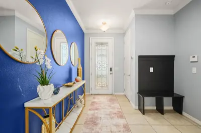 a hallway with blue walls and a table and a mirror at 4 Mi to Dtwn Home with Pool Access in Sanford in Sanford