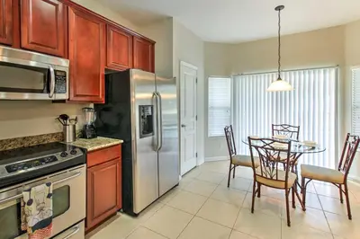 a kitchen with a table and a stainless steel refrigerator at Spacious Kissimmee Villa - 3 Mi to Disney World! in Orlando