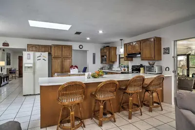 a kitchen with wooden cabinets and bar stools at Spacious Central Florida Home Family Friendly! in Orlando