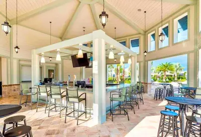 a covered patio with tables and chairs and a bar at Lovely 2BR Codo with 2Clubhouses & Kids Splash Pad in Kissimmee