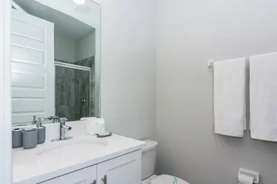 a white bathroom with a sink and a mirror at Amazing Home w a Private Pool in Orlando