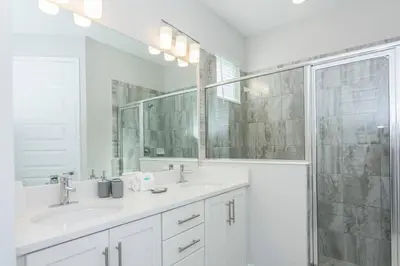 a white bathroom with two sinks and a shower at Amazing Home w a Private Pool in Orlando