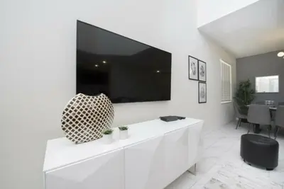 a white living room with a large tv on a wall at Gorgeous 5 Beds Home with Game Room and Pool in Kissimmee