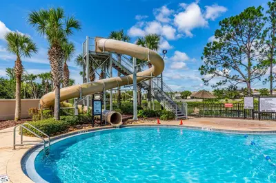a swimming pool with a water slide at a resort at Our Mickey Mouse House Townhome with Pool! in Orlando