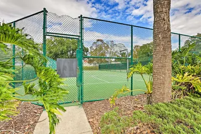 a tennis court behind a fence with a tree at 7 Mi to WDW Indian Ridge Home with Pool Access! in Orlando