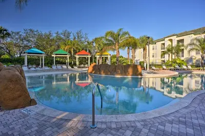 a swimming pool at a resort with trees and buildings at Lake-View Condo with Pool Access 6 Mi to Disney! in Kissimmee