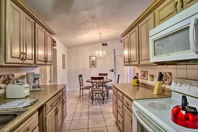 a kitchen with wooden cabinets and a table with chairs at Kissimmee Home 5 Mi to Gatorland and 15 Mi to Disney in Kissimmee