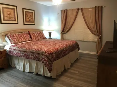 a bedroom with a bed with a red comforter and a window at 7 Bedroom, 6 bath and pool near Disney in Emerald Island 4 King Master Suites in Kissimmee