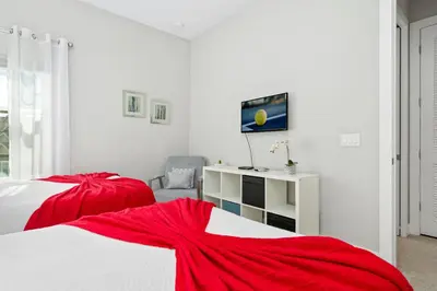 a white bedroom with two beds with red sheets at 5min Disney Cozy Villa, BBQ Grill, SMV108 in Orlando