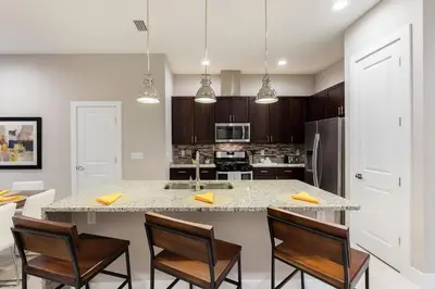 a kitchen with a large island with chairs and a counter top at 4 BR 4 BA Deluxe Villa 5 min to Disney Family getaway in Orlando
