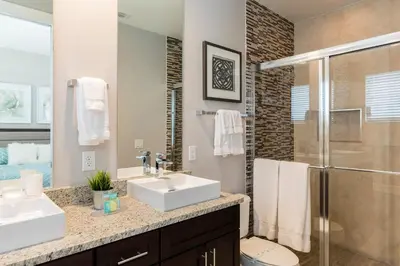 a bathroom with two sinks and a shower at 4 BR 4 BA Deluxe Villa 5 min to Disney Family getaway in Orlando
