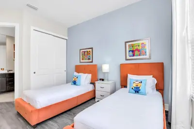 two beds in a bedroom with white and orange at 5 BR 6 BA Luxury Villa 5 min to Disneyworld Hot Tub & BBQ 112 in Orlando