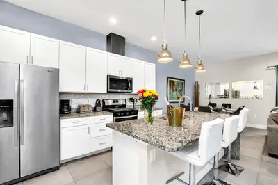 a kitchen with white cabinets and a granite counter top at 5 BR 6 BA Luxury Villa 5 min to Disneyworld Hot Tub & BBQ 112 in Orlando