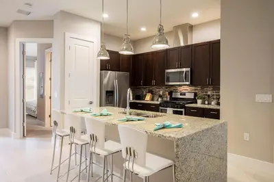 a kitchen with a large island with white bar stools at Gorgeous Family Villa 114 in Orlando