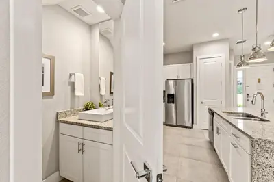 a white kitchen with a sink and a refrigerator at Ultra convenient stay, 5 min to Disney SMV118 in Orlando