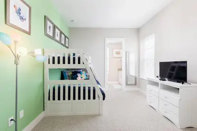 a childs room with a crib and a tv at Amazing Family Villa 5min Disney w BBQ 128 in Orlando