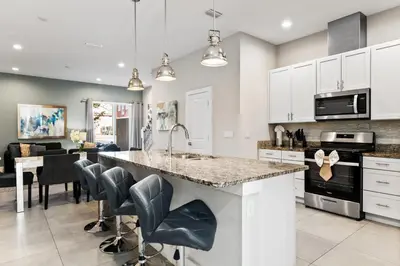a kitchen with white cabinets and a large island with bar stools at 5min to Disney Spacious Family Villa SMV135 in Orlando
