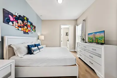 a bedroom with a white bed and a flat screen tv at 5min to Disney Spacious Family Villa SMV135 in Orlando