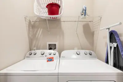 a laundry room with two washing machines and a basket at Amazing Hidden Gem, Min Disney 139 in Orlando