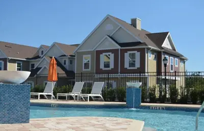 a pool with chairs and an umbrella in front of a house at Amazing Family Villa, 5min Disney SMV144 in Orlando