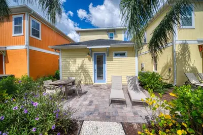 a patio with a table and chairs in front of a house at Sunny Yellow Cottage Near Disney With Margaritaville Resort & Island H2O Access - 3029Sp in Orlando