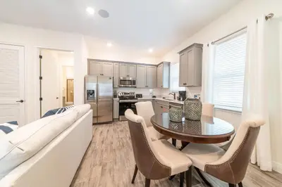 a kitchen and dining room with a table and a couch at Sunny Yellow Cottage Near Disney With Margaritaville Resort & Island H2O Access - 3029Sp in Orlando