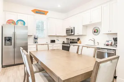 a kitchen with a wooden table and a stainless steel refrigerator at Margarita Beach House Cottage Near Disney With Private Hot Tub & Island H20 Waterpark Access - 3074Pi in Orlando