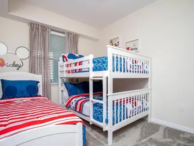 a white bedroom with a red white and blue bed at Marvelous 2 Bd Apt Close to Disney at Storey Lake 106 in Kissimmee