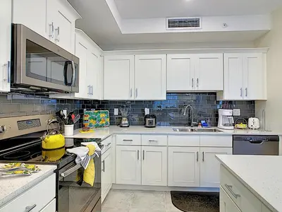 a white kitchen with white cabinets and appliances at Fabulous Thematic 2BR Condo with Kids Splash Pad in Kissimmee