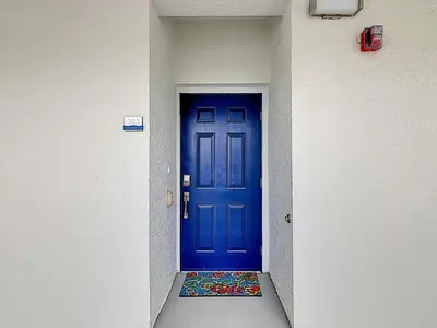 a blue door in a hallway with a mat in front at Fabulous Thematic 2BR Condo with Kids Splash Pad in Kissimmee