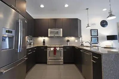 a kitchen with stainless steel appliances and black cabinets at Beautiful 3-Bed Villa 10 Minutes From Disney-17440 Serenity Resort townhouse in Orlando