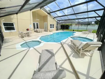 a swimming pool with chairs and a glass roof at Mickeys Circle - Gorgeous! Modern 6BR, with Private South Facing Pool Hot Tub BBQ Theater 2 Miles to Disney in Orlando