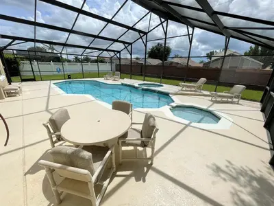 a patio with a table and chairs and a pool at Mickeys Circle - Gorgeous! Modern 6BR, with Private South Facing Pool Hot Tub BBQ Theater 2 Miles to Disney in Orlando