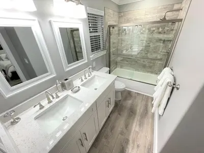 a white bathroom with two sinks and a shower at Mickeys Circle - Gorgeous! Modern 6BR, with Private South Facing Pool Hot Tub BBQ Theater 2 Miles to Disney in Orlando