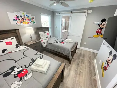 a bedroom with two beds with mickey mouse decorations on the walls at Mickeys Circle - Gorgeous! Modern 6BR, with Private South Facing Pool Hot Tub BBQ Theater 2 Miles to Disney in Orlando