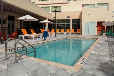 a swimming pool in a hotel with chairs and umbrellas at Aloft Orlando Lake Buena Vista in Orlando