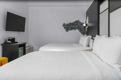 a bedroom with two white beds and a flat screen tv at Aloft Orlando Lake Buena Vista in Orlando