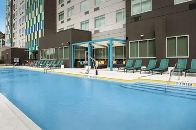 a large swimming pool with chairs and a building at Tru By Hilton Orlando Convention Center in Orlando