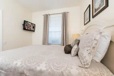 a bedroom with a white bed with pillows and a window at Beautiful Condo - Windsor Hills - 2 Miles Disney in Orlando
