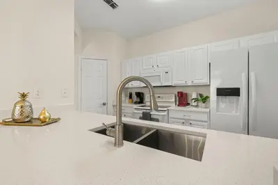 a kitchen with white cabinets and a stainless steel refrigerator at Ground Floor at Windsor Hills – 5 Min Disney in Orlando